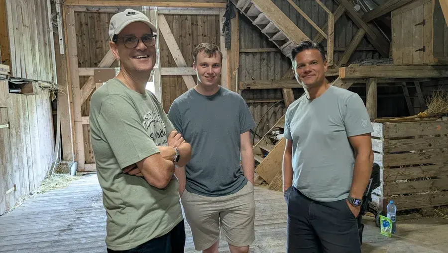 Drei Mitarbeiter des Previon-Teams posieren gemeinsam in der Holzscheune des Eventorts